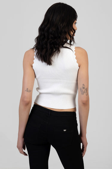 back view of a woman in a white ribbed sleeveless knit top with scalloped edges paired with black jeans