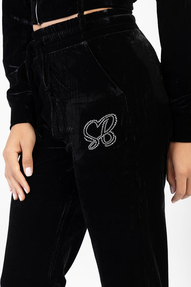 black velour track pants with a rhinestone monogram on the left thigh, elastic waist and pockets