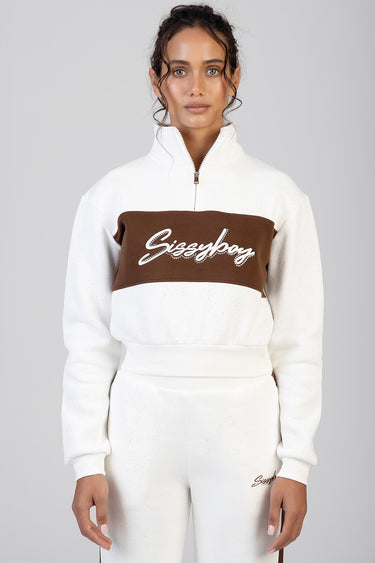 woman wearing a white track top with a brown chest band, zip collar, and a white script logo across the front.