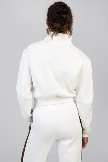 back view of a model wearing a white speckled track top with a ribbed collar and cuffs, paired with white pants featuring a