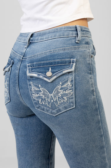 blue denim jeans close up showing back pocket with white embroidered wings and small metal button