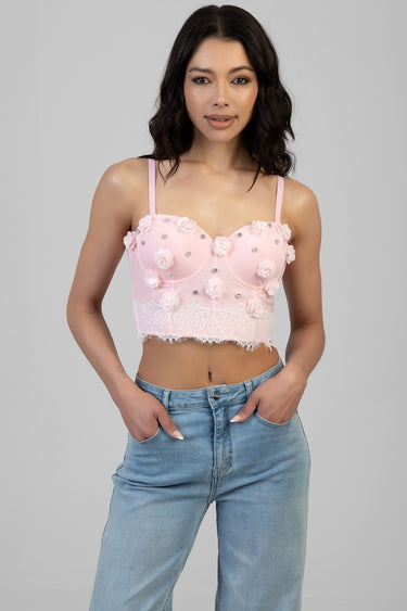 pink corset top with floral appliqués and lace trim, worn by a woman in light blue jeans