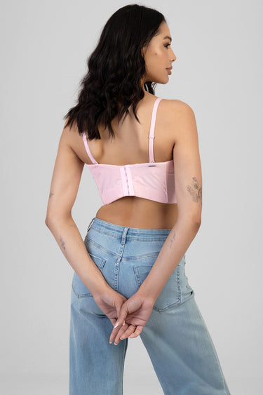 woman in light pink corset top with adjustable straps and back closure, wearing blue jeans, back view