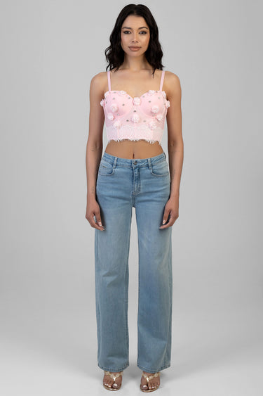 woman wearing pink cropped corset top with floral lace and bead details, spaghetti straps, paired with light wash wide leg