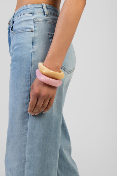 three resin bangles in pink peach and yellow on a model wrist with light wash jeans
