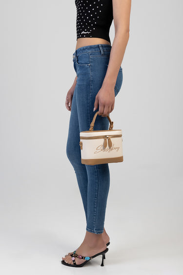 woman in blue jeans holding a beige and tan mini vanity bag with top handle and gold zipper accents