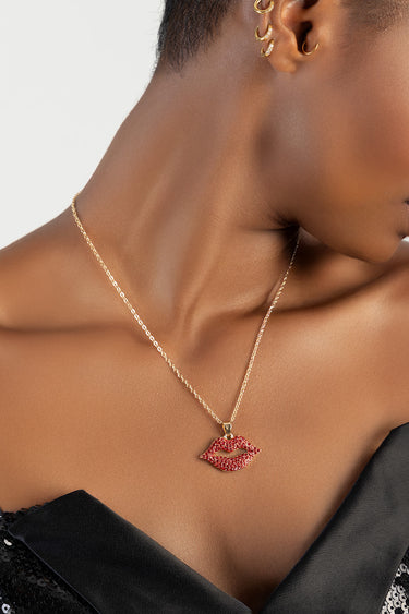 model wearing a gold lip shaped pendant necklace with red stones on a delicate chain