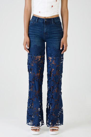 model wearing dark blue denim jeans with navy floral lace panels from mid thighs to ankles, wide leg, paired with white