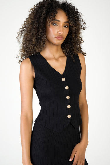 black ribbed knit waistcoat with a gold button placket worn by a model in a matching knit top by Blue Jean Traders