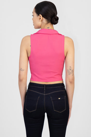 back view of a woman in a bright pink sleeveless cropped top with a collar and dark denim jeans