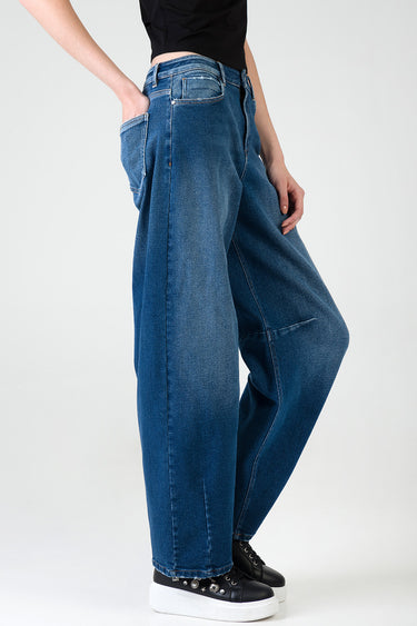 model wearing blue indigo denim jeans with wide legs and large pockets, paired with black sneakers