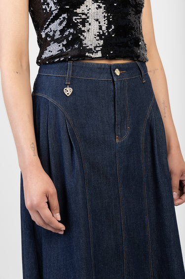 woman wearing a dark blue denim skirt with front vertical seam panels, orange stitching, belt loop charm, and a black