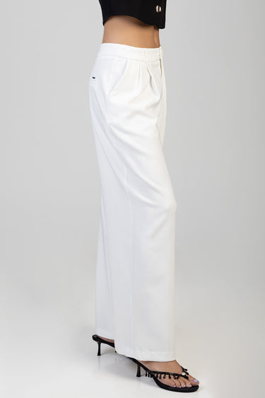 side view of white wide leg trousers with pleats and belt loops worn with black top and heeled sandals