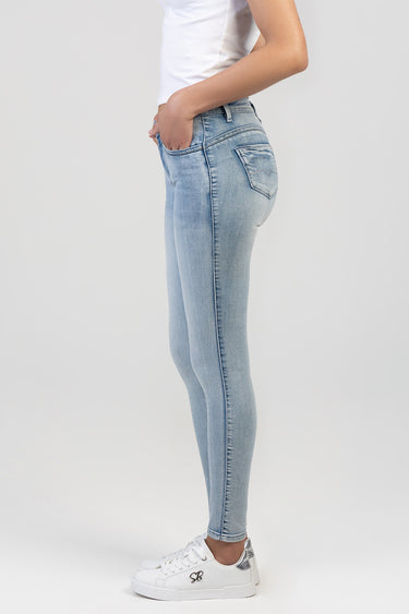 light blue skinny jeans on a model, side profile, back pocket with stitched detail, white sneakers