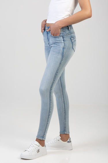 side view of a model in light blue skinny jeans with a white top and white sneakers