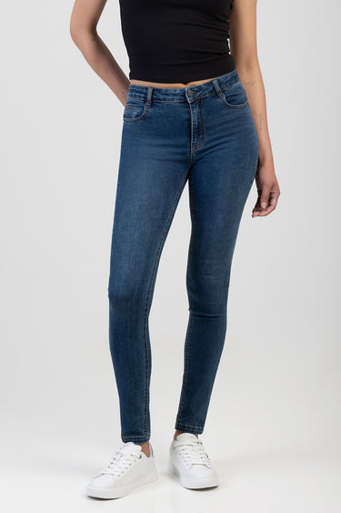 Blue Jean Traders blue skinny jeans on a model wearing a black top and white sneakers