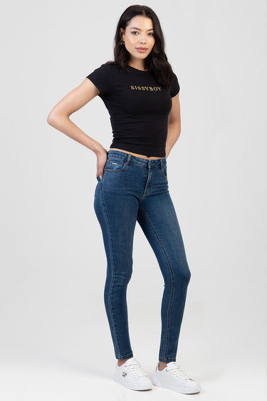 woman wearing blue skinny jeans, a black cropped t shirt with gold lettering, and white sneakers