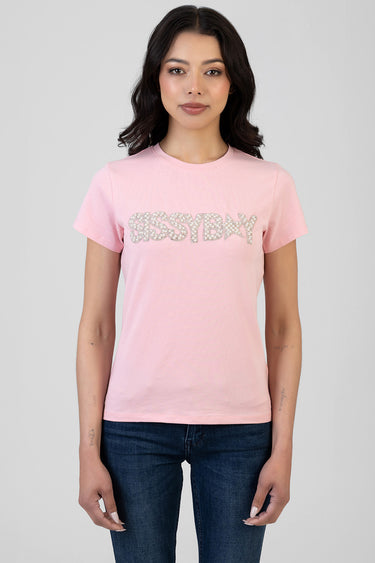 woman wearing a pink short sleeve t shirt with a silver rhinestone text graphic across the chest