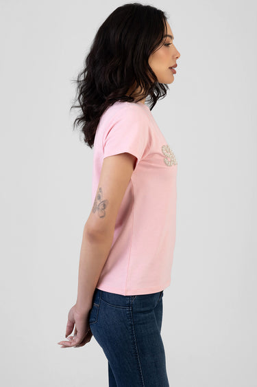 side view of a woman wearing a light pink short sleeve t shirt with a rhinestone embellishment