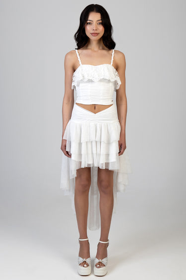 woman modeling a white lace crop top with spaghetti straps and a layered high low skirt with ruffles, wearing white