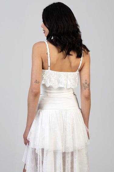 woman wearing white lace crop top with adjustable straps and a tiered sheer skirt seen from the back