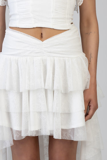 woman in a white ruched crop top and a layered lace skirt with multiple tulle tiers