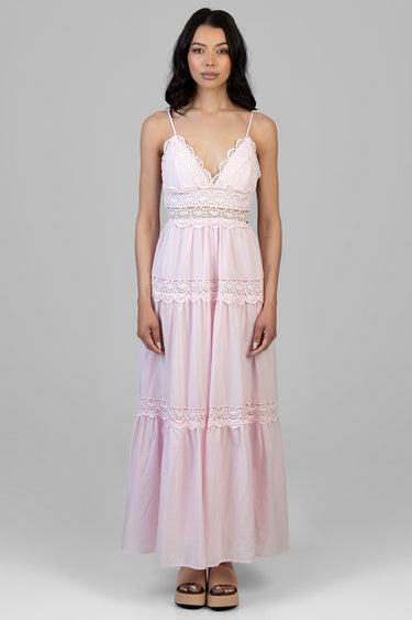 woman in blush pink lace maxi dress with spaghetti straps standing against a grey background