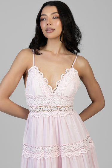 woman in pale pink lace maxi dress with scalloped trim, thin straps, and tiered skirt