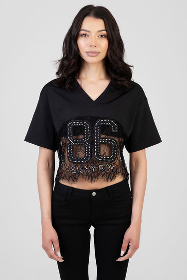 woman wearing a black cropped boxy t-shirt with short sleeves and a lace panel with a studded eighty six on the chest