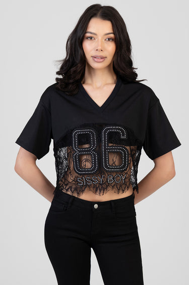 woman wearing a black v neck cropped top with short sleeves, lace panels, and rhinestone eighty six with sissy boy lettering