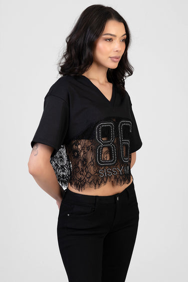 woman in black short sleeve cropped top with lace hem and a rhinestone studded eighty six graphic