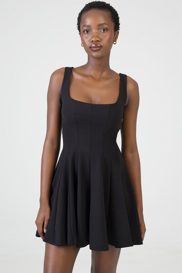 model wearing a black sleeveless fit and flare dress with wide straps and square neckline