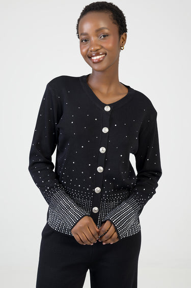 woman wearing a black knit cardigan with silver buttons and scattered white dots, gradient dot pattern at cuffs and hem