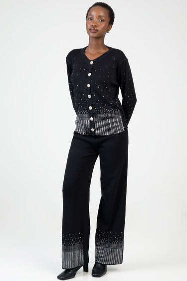 woman wearing a black knit cardigan with silver dot pattern and large buttons, paired with black wide-leg pants with a