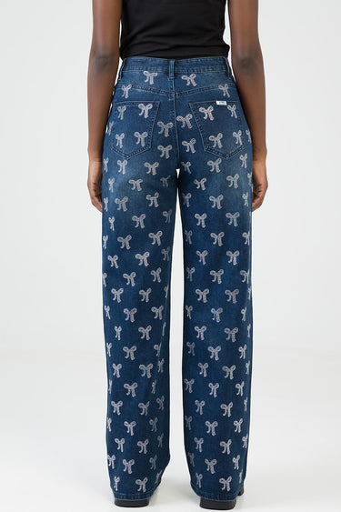 back view of a person wearing blue wide leg jeans with white bow patterns all over, back pockets visible