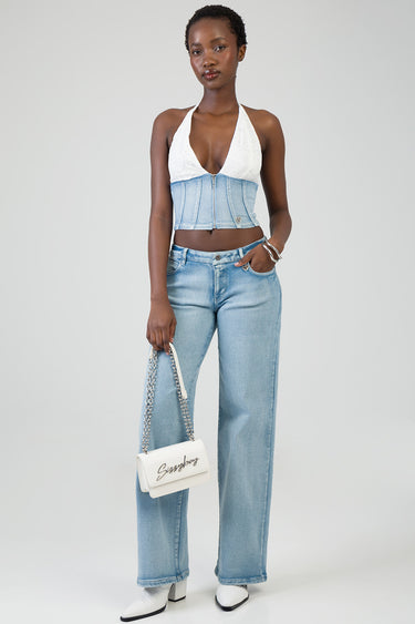 model in white lace halter top and light blue denim corset belt with wide leg jeans, carrying a white crossbody bag with a