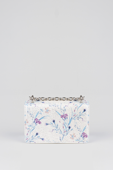 white perforated bag with a blue and purple floral print and a silver chain strap