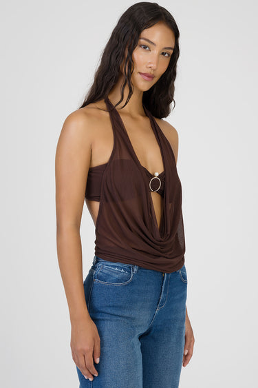 woman wearing a brown draped halter top with a circular ring accent over a bralette, paired with blue denim jeans