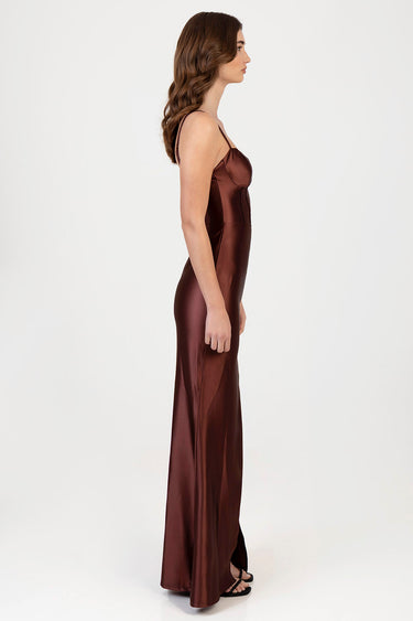 side view of a model in a brown satin maxi dress with thin straps and a fitted bodice