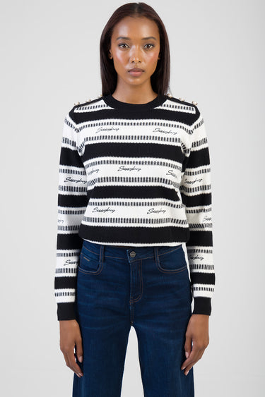 woman wearing a black and white striped knit sweater with pearl buttons on the shoulders and logo embroidery