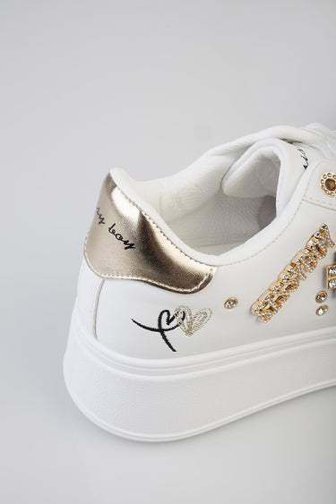white sneakers with a metallic gold heel patch, rhinestone detailing and heart embroidery