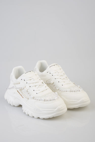 white sneakers with pearl bead embellishments and chunky sole on a pale background