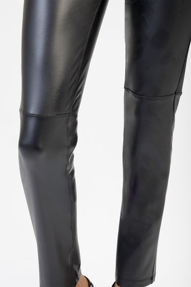 close up of black faux leather jeans on legs, glossy finish and seam details at knee and ankle