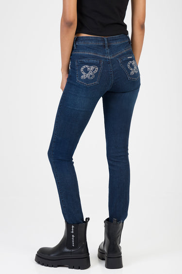 back view of woman in dark blue skinny jeans with crystal heart designs on back pockets and chunky black boots