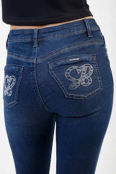 back view of dark blue skinny jeans with rhinestone heart designs on the pockets and a small brand label