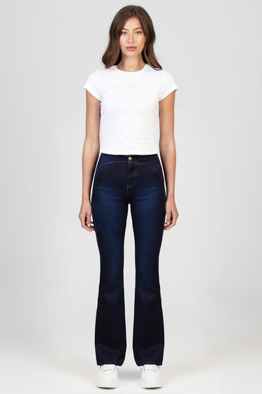 woman wearing dark indigo flare jeans with white sneakers and a white fitted t shirt