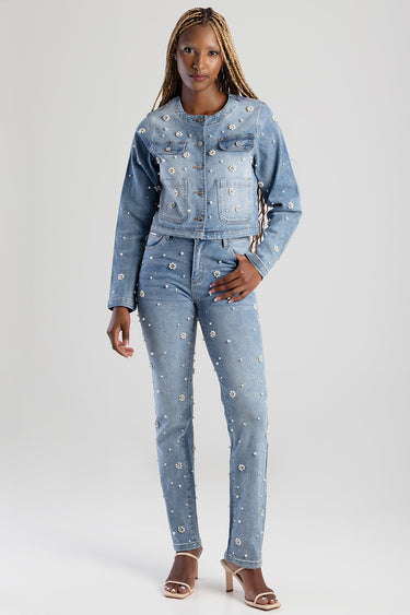 woman wearing a light blue denim jacket and matching jeans with pearl embellishments; cream heeled sandals.
