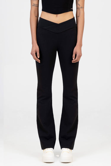 model wearing black knit denim pants with a crossover waistband and white sneakers