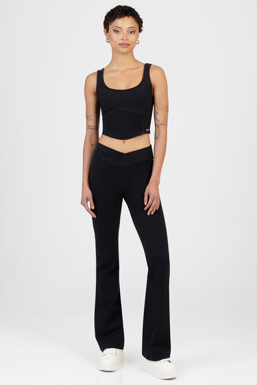 woman wearing black knit denim pants with a high waist and flared legs, paired with a black tank top and white sneakers