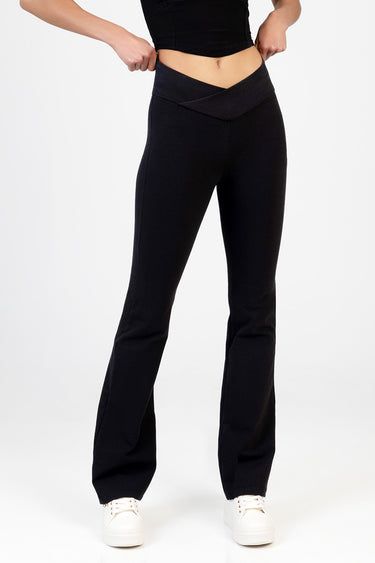 woman wearing black knit denim pants with a crossover waistband and straight full length legs, white sneakers